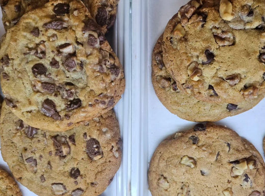 Assorted cookies with chocolate chips, nuts, and white chocolate chips on a white tray.
